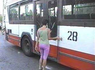 Woman opening door of bus from outside in order to get in through back