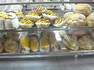 A glass display at a bakery, with several kinds of baked goods