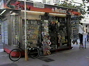 A small outdoor newsstand selling snacks, cigarettes, and other miscellaneous items