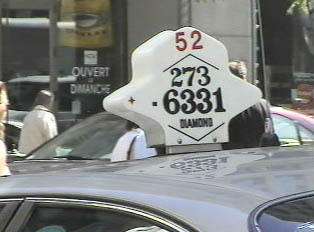 A white sign on top of a taxi, displaying a phone number
