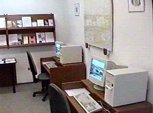 A couple of desks with white computer monitors on top