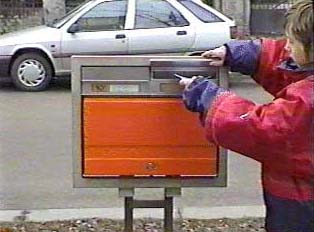 A child putting mail in an orange mailbox