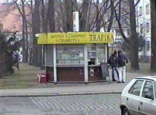 Two people at an outdoor newsstand, called "Trafika"