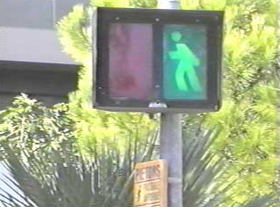 A green walk sign at a pedestrian crossing