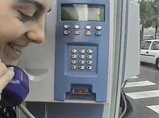 A person smiling while using a public phone