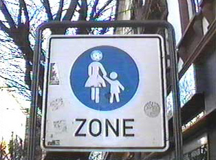 A pedestrian zone sign, picturing a woman walking with a child
