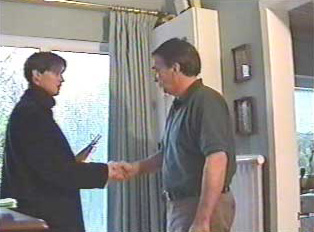 Two people shaking hands at the entrance of a home