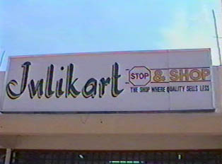 A sign outside a supermarket that reads 'Julikart: stop and shop, the shop where quality sells for less'