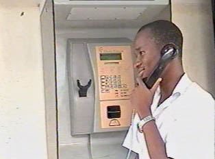 A person talking to someone on a public pay phone outdoors