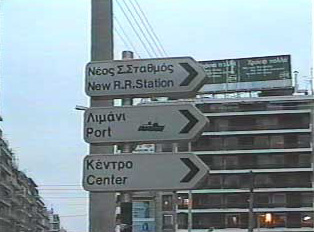 A road sign for a railway station, seaport, and city center