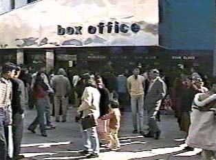 Multiple people gathered outside a movie theater box office