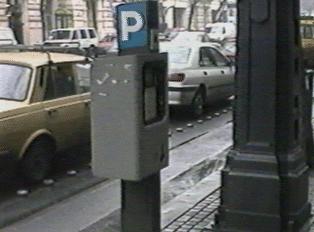A gray parking meter, indicated by a blue 'P' sign on top