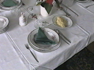 A table set nicely for a meal, with white tablecloths, folded napkins, plates, and silverware