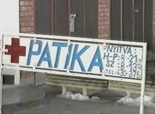 A white sign with blue letters and a red cross, indicating a pharmacy