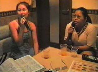 Two people singing karaoke in a bar