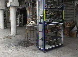 A telephone sitting on a small stand, next to a shelf of goods