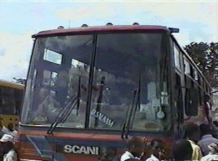The front of a red bus with passengers waiting to board