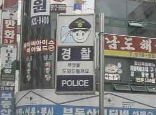 A blue and white sign with a cartoon policeman saluting, indicating a police station