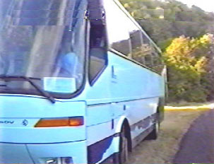 A large blue bus parked off the side of a road