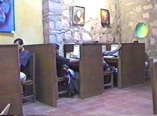 Three people seated in booths at an internet cafe