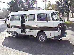A small white and red public transportation van, stopped on the road