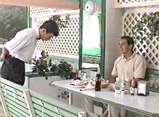 A waiter attending to a man eating outside at a restaurant