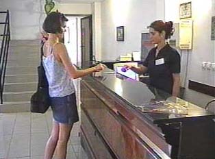 A person reserving a room at a hotel counter