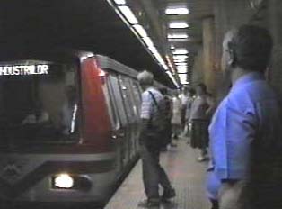 A red subway car stopped to collect passengers