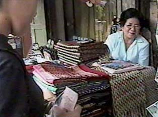 Two people standing next to a table of textile goods