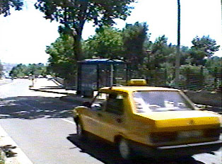 A yellow taxi driving down the street