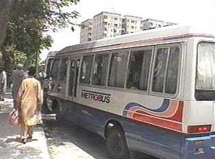 A white metrobus with colorful lines along the side