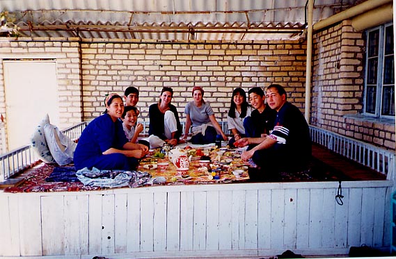 Turkmen family and their American friends eating breakfast on tapchan
